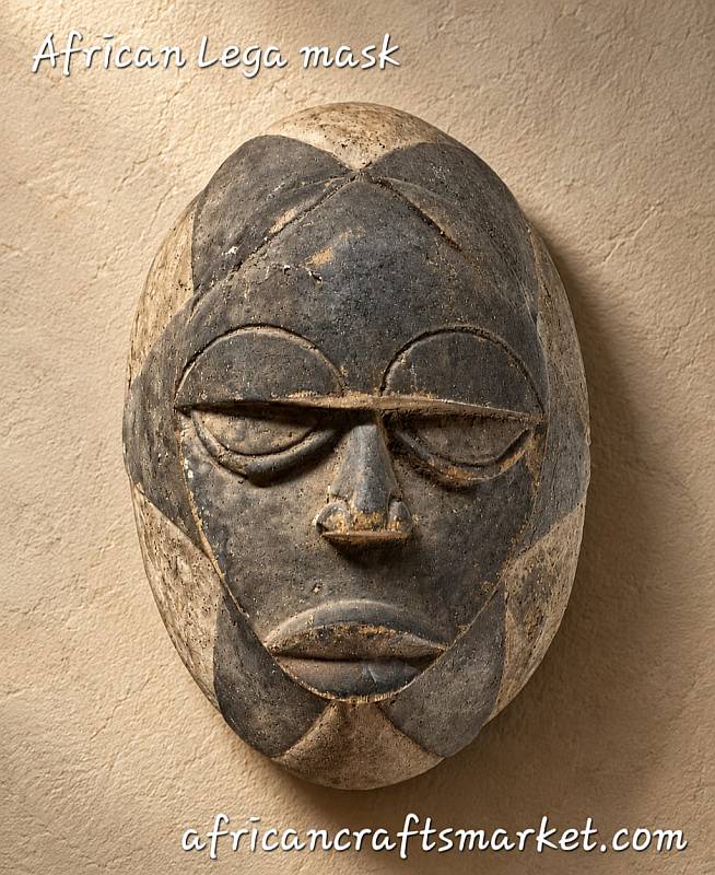 Hand-carved African Lega mask made of wood and white kaolin clay, featuring traditional almond eyes and dot-and-circle motifs from the Bwami Society of the Congo