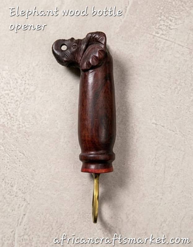A handcrafted African wooden bottle opener beautifully carved into the shape of an elephant with an upright trunk, featuring detailed hand-painted touches and a sturdy integrated metal opener