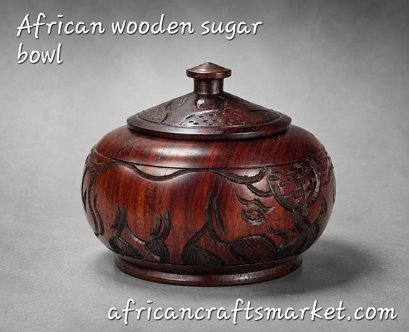 A rustic hand-carved African wooden bowl used as a decorative countertop storage piece in a modern kitchen setting